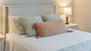 A bed with a quilted bedspread, a headboard with a herringbone pattern, and two bedside lamps.