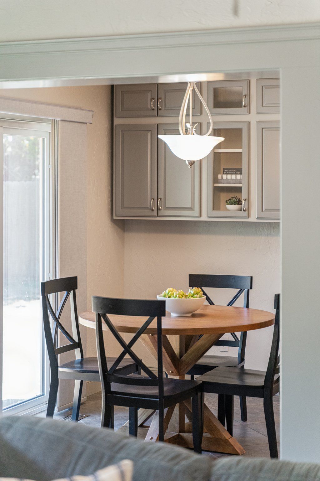 A dining area with a round table, four chairs, and a bowl of food.