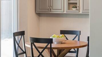 A dining area with a round table, four chairs, and a bowl of food.
