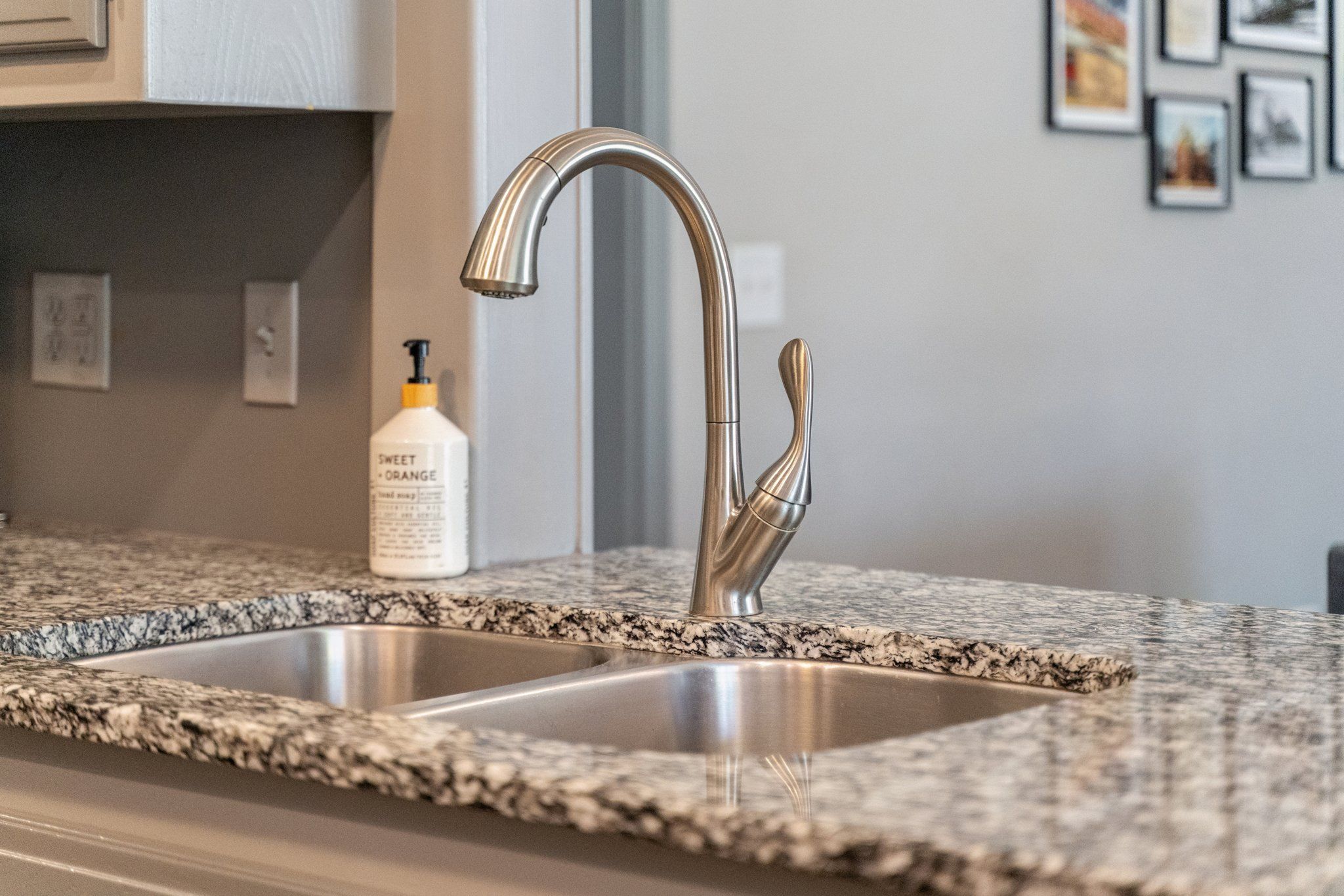 A kitchen with a stainless steel sink and a granite countertop.