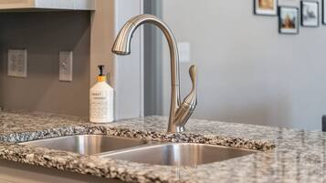 A kitchen with a stainless steel sink and a granite countertop.