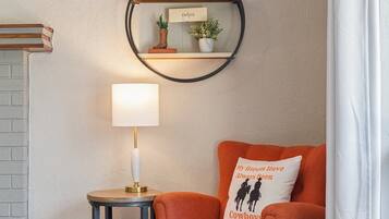 A cozy corner with a round wall shelf, a lamp, a cushioned chair, and a decorative pillow.