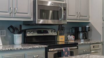 A kitchen with stainless steel appliances, including a microwave, oven, and coffee maker.