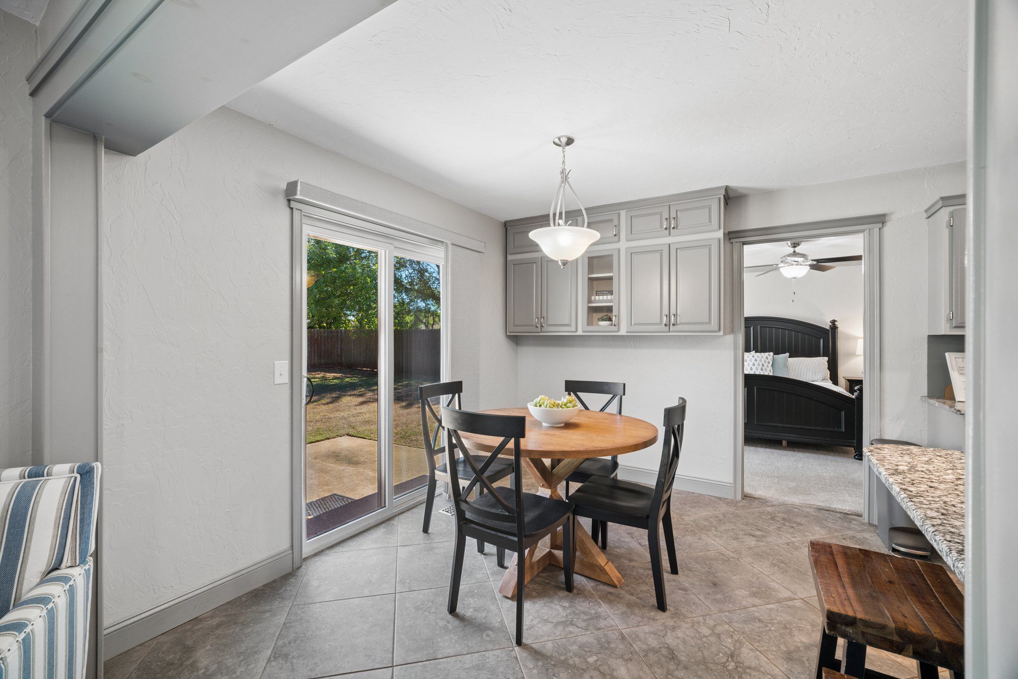 A compact kitchen with a dining area, a ceiling fan, and a view through the glass sliding doors.