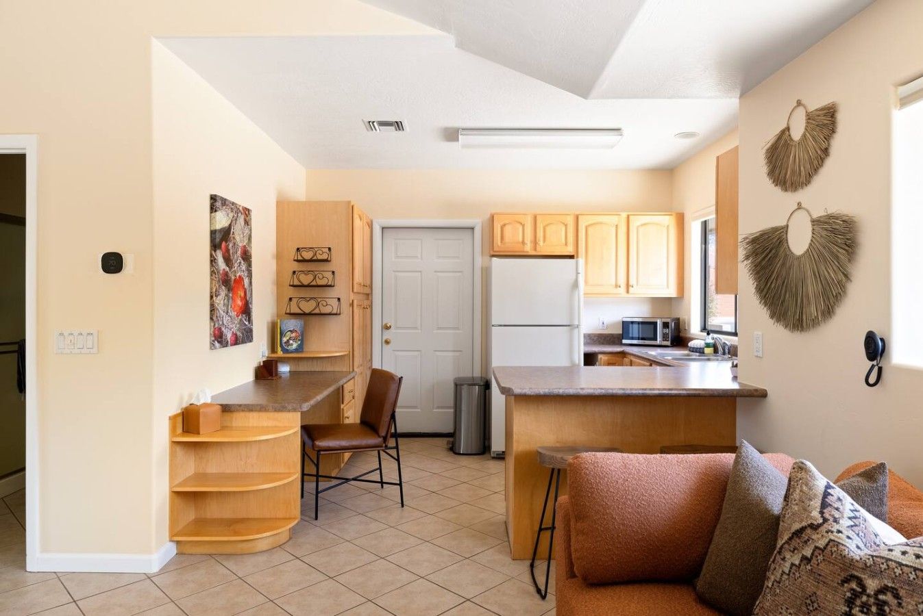 A compact kitchen with a refrigerator, microwave, and wooden cabinets.