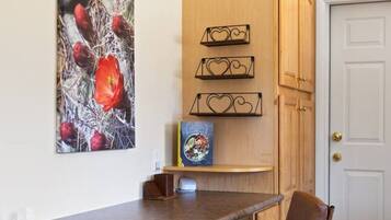A kitchen with wooden cabinets, a white door, a brown chair, and a painting of red flowers.