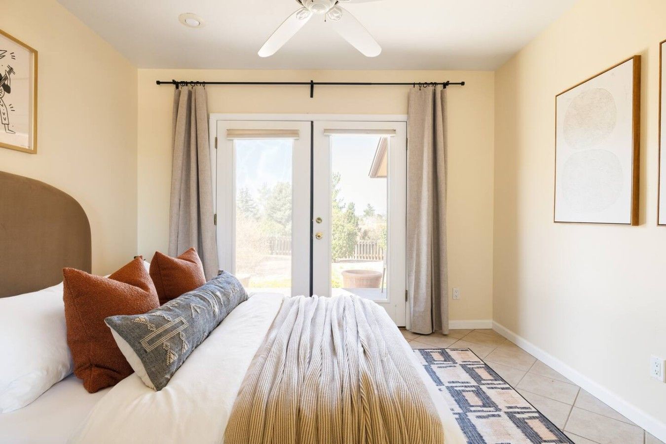 Ein Schlafzimmer mit Bett, Vorhängen, Deckenventilator und Blick durch eine Tür.