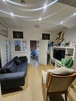 Una sala de estar moderna con un sofá, una silla, un televisor y un comedor con una mesa y sillas.