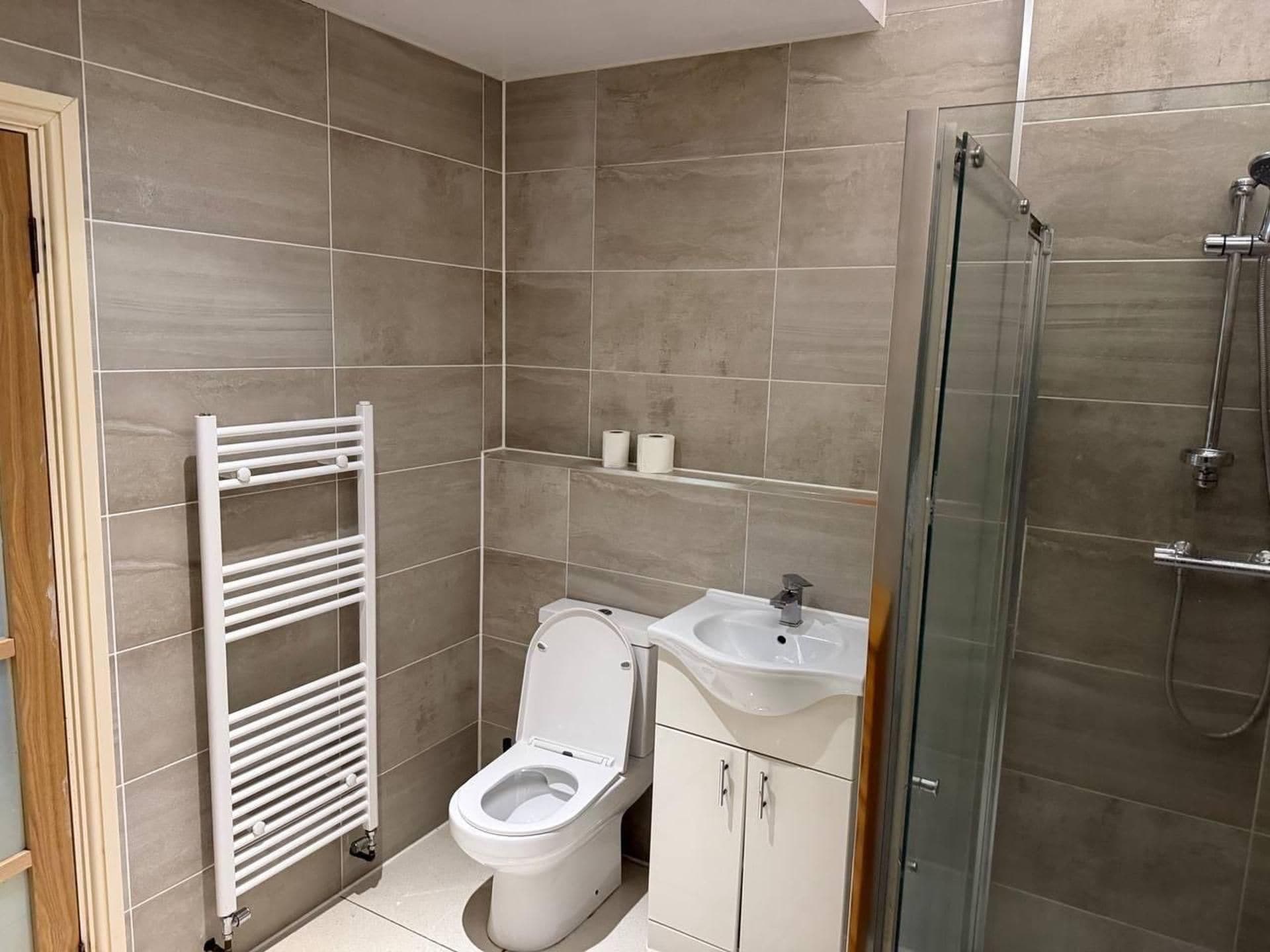 Un baño pequeño con inodoro, lavamanos y ducha.