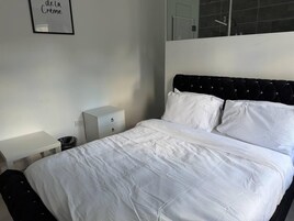 Un dormitorio con una cama, una mesita de noche, un aparador y un cuadro en la pared.