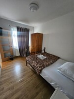 Un dormitorio con cama, armario, radiador y ventana con cortinas.