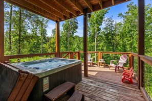 A wooden deck with a hot tub, outdoor seating, and a view of a forest. - The Sporting Place - Outdoor Hot Tub, Firepit, Game Room + Close to Pigeon Forge (Sevierville)