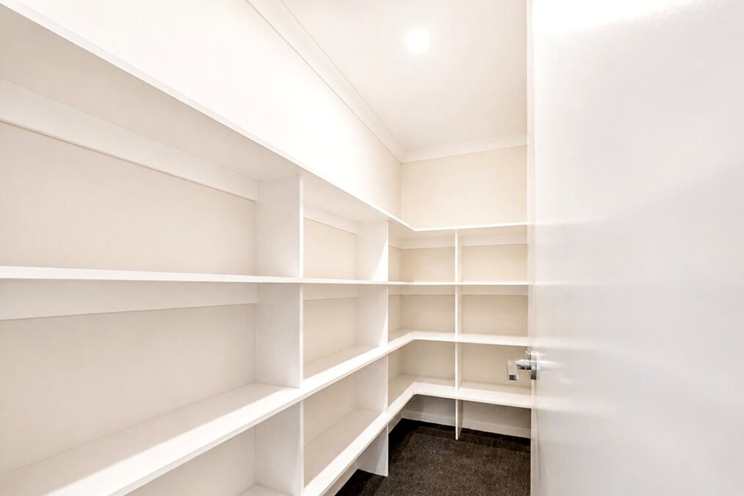 Ein weißer Schrank mit mehreren Einlegeböden und einer Tür.