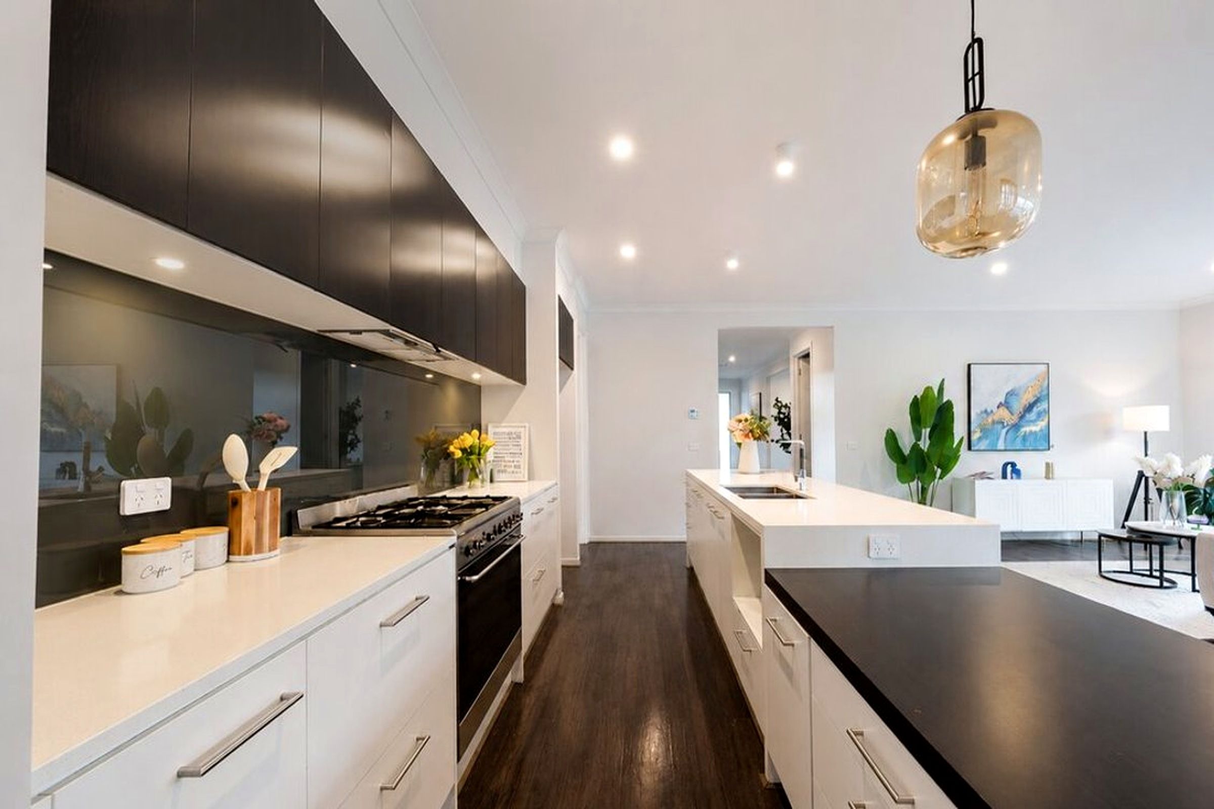 A modern kitchen with dark cabinetry, a central island, and a pendant light.