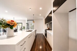 Cuina moderna amb una illa central, electrodomèstics integrats i zona de menjador amb vistes.