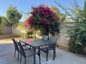 Un patio con mesa y sillas, rodeado de vegetación y una valla de madera.