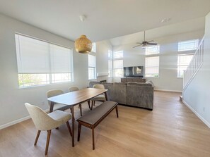 Un vaste espace de vie comprenant une table à manger, des chaises, un canapé et un téléviseur.