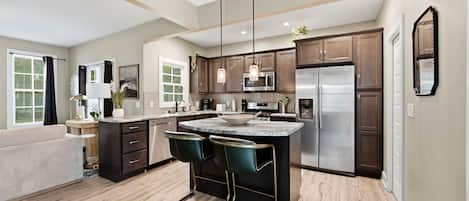 A modern kitchen with a central island, stainless steel appliances, and pendant lighting.