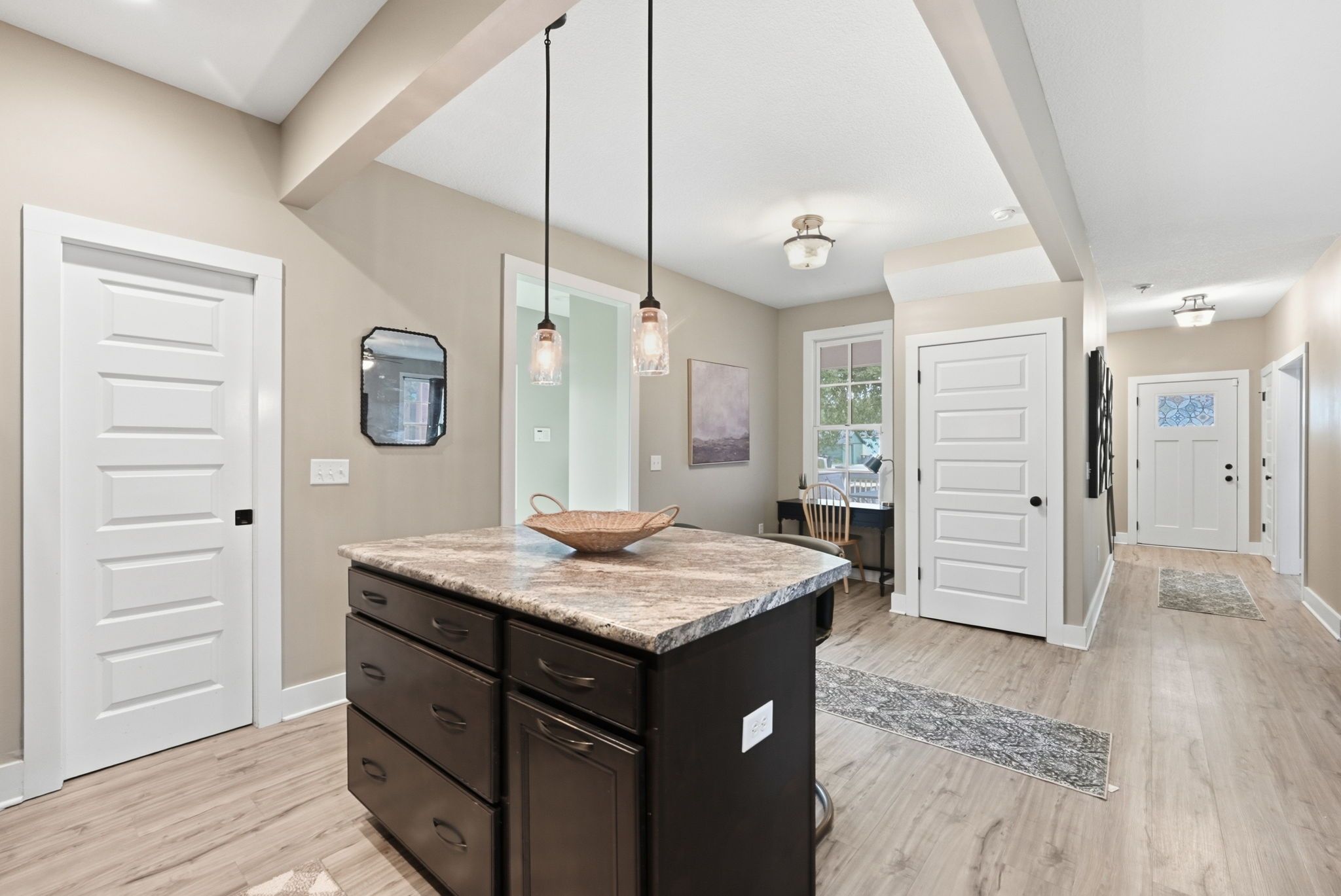 A spacious kitchen with a central island, pendant lighting, and a view into the dining area.