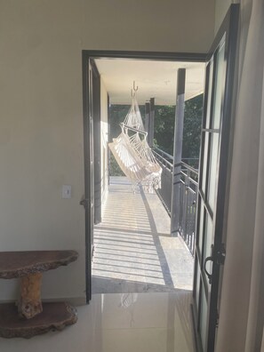 An open doorway leading to a balcony with a hammock, a wooden bench, and a tiled floor. - Cozy Mediterranean Chalet (Alcalá)