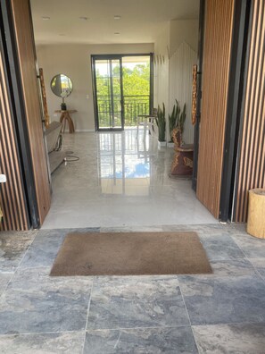 A spacious entrance with a polished floor, a brown doormat, and a view through a glass door to an outdoor balcony. - Cozy Mediterranean Chalet (Alcalá)