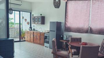 A modern kitchen with a refrigerator, stove, and cabinets, a dining area with a table and chairs, and a patterned floor.