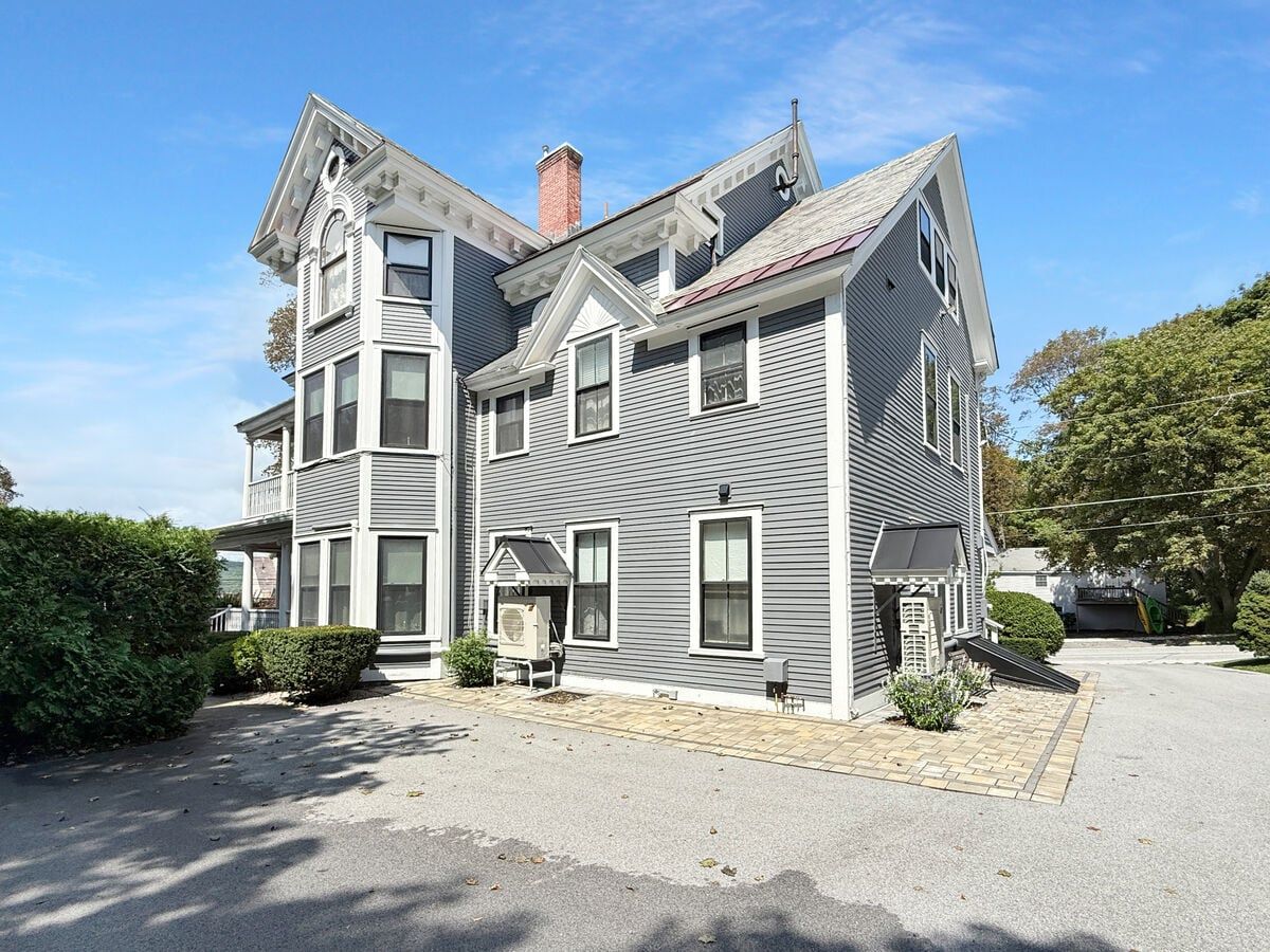 A two-story house with a central entrance, a covered porch, and a chimney.