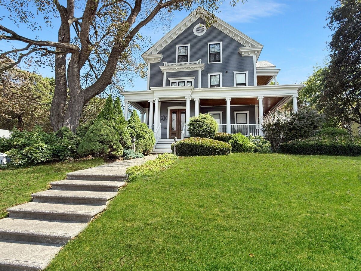 A two-story house with a front porch, a stone staircase leading to the front door, and a well-maintained lawn.