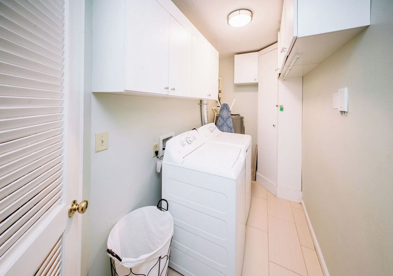 A compact bathroom with a white washing machine, a small white basin, and a towel rack.