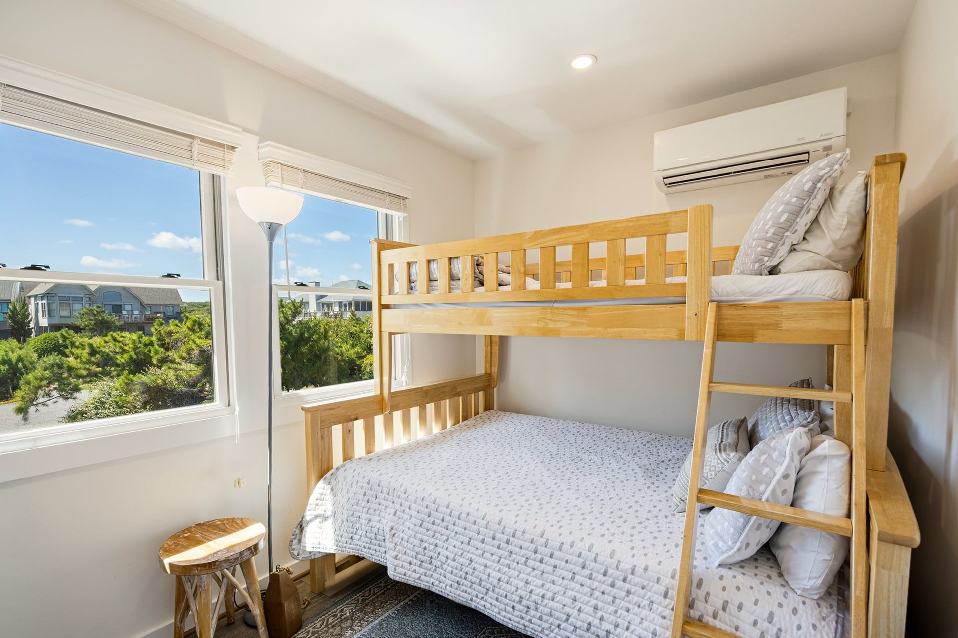 A bunk bed room with a window, a standing lamp, and an air conditioning unit.