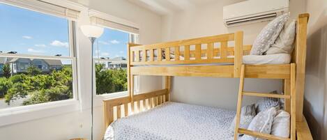 A bunk bed room with a window, a standing lamp, and an air conditioning unit.