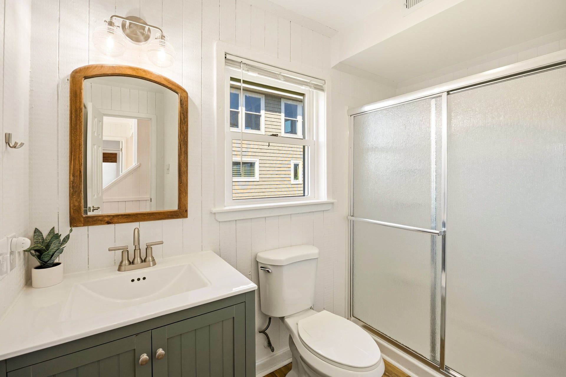 A bathroom with a white sink, a toilet, and a shower enclosure.