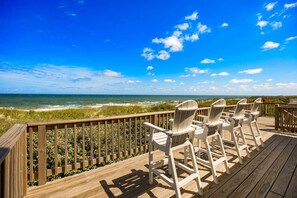 A wooden deck with Adirondack chairs overlooking a beach. - Half Moon Haven Ocean-view, hot tub, pool, and beach access. (Duck)