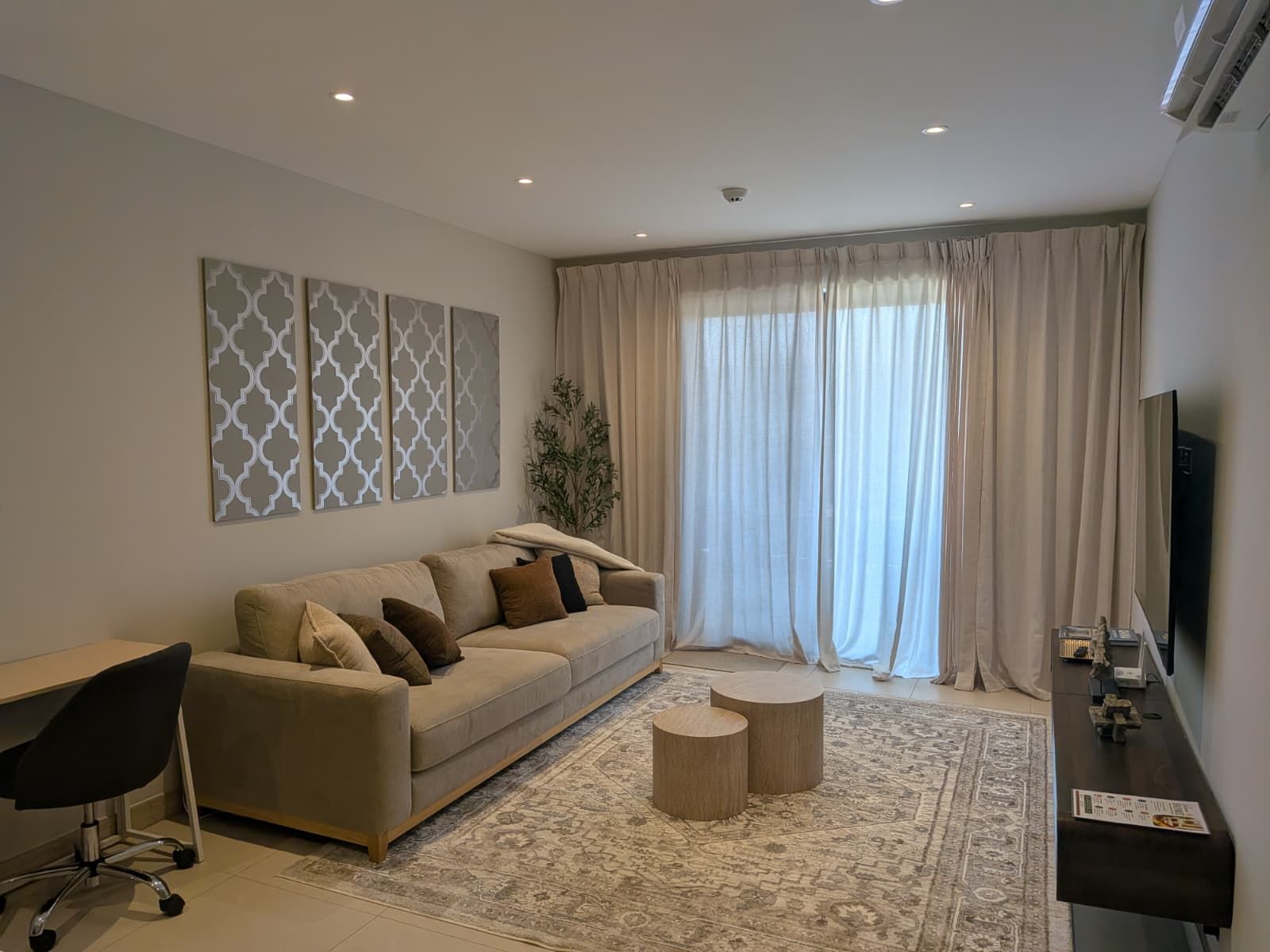 Ein modernes Wohnzimmer mit einer Couch, einem Schreibtisch, einem Sessel und einem Fernseher.