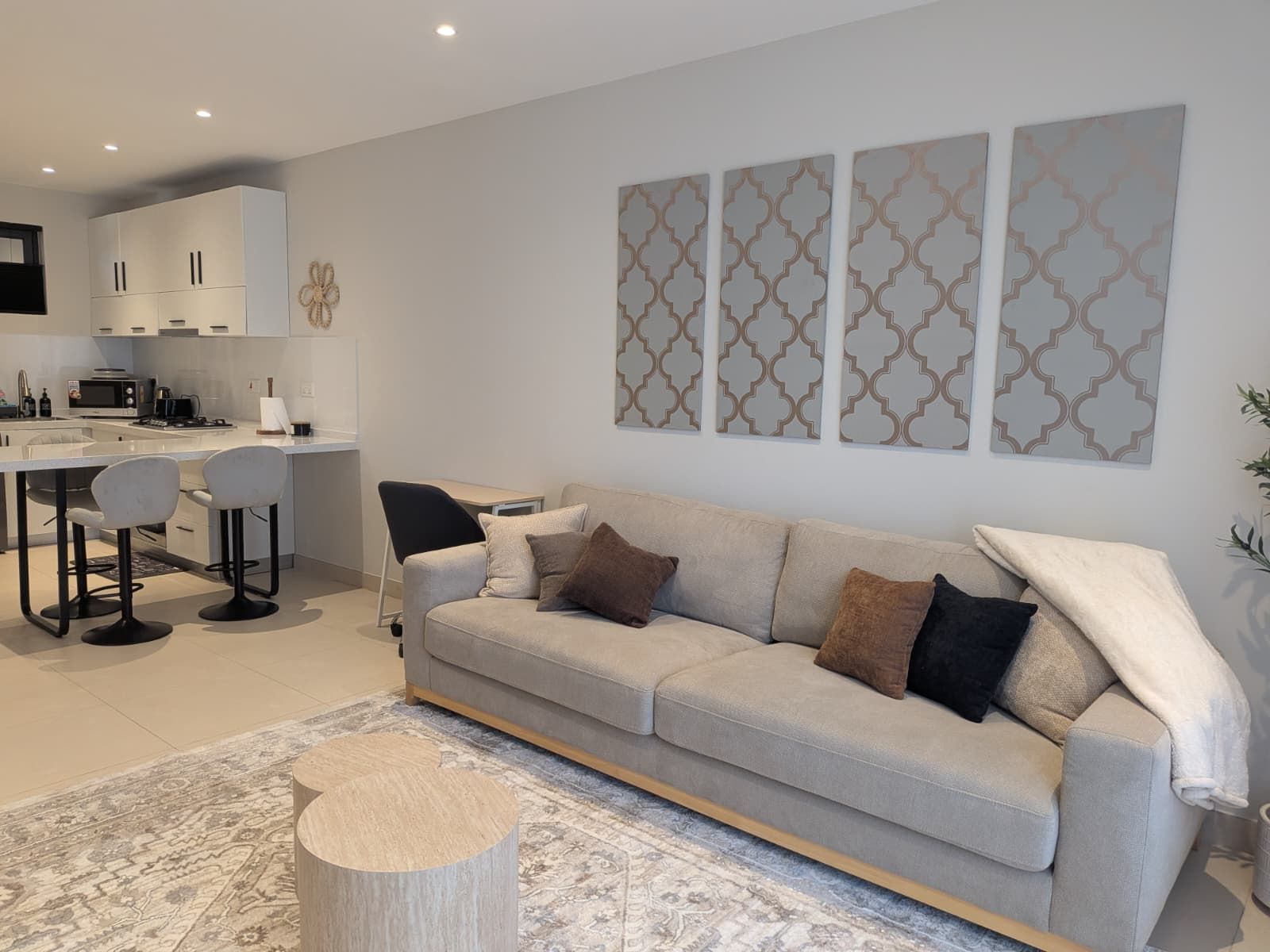 A modern living room with a sofa, a coffee table, and a kitchen area with cabinets and a microwave.