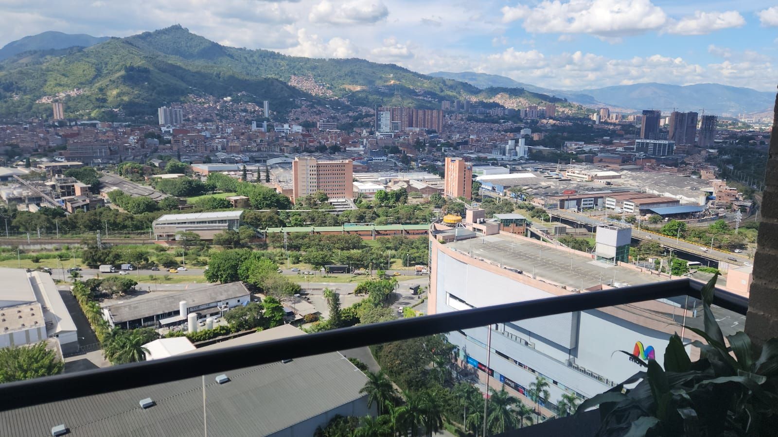 A cityscape with a mix of residential and commercial buildings, a prominent hill in the background, and a clear sky.