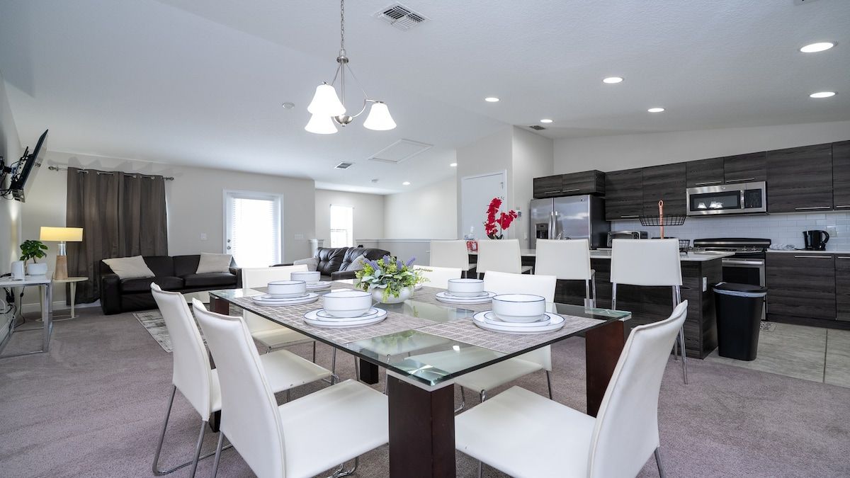 A modern kitchen with dark cabinetry, a stainless steel refrigerator, and a microwave.