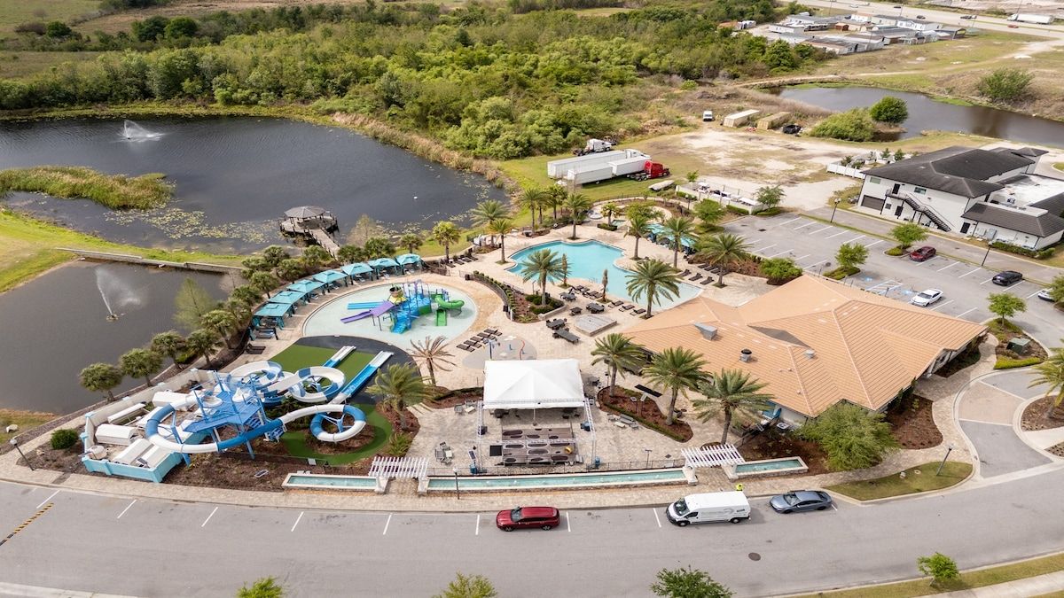 An aerial view of a resort with a swimming pool, water park, and a large building with a sloped roof.