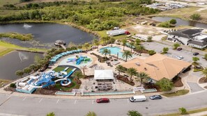 Vista aérea de un resort con piscina, parque acuático y un edificio grande con techo inclinado.