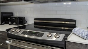 Una cocina con estufa de acero inoxidable, un tostador y un microondas.