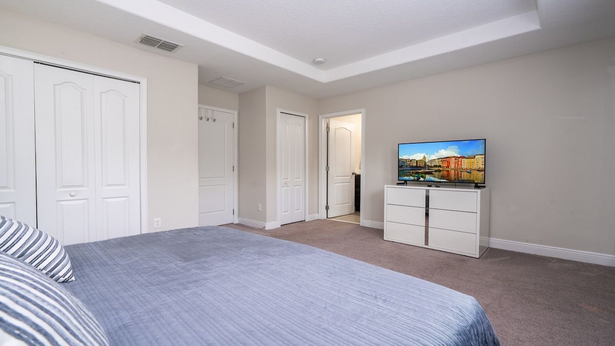 Quarto com cama, televisão, penteadeira e guarda-roupa.
