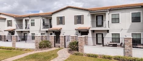 A row of townhouses with stone accents, balconies, and a paved walkway.