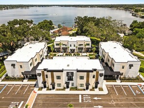 Hotel amb un pati central, envoltat de places d'aparcament i una massa d'aigua al fons.