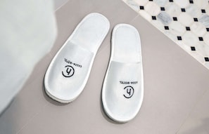 Weiße Slipper mit einem Logo und Schriftzug auf der Sohle.