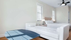 Et hotelværelse med seng, natbord, lampe, ventilator i loftet og et lille bord.