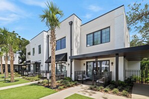 A modern building with a flat roof, large windows, and a covered outdoor seating area. - Cassa Orlando: Luxury Poolside 1BR/2BA Unit 106 (Orlando)