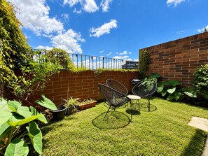 A well-maintained outdoor area with a brick wall, a metal fence, and a grassy lawn.