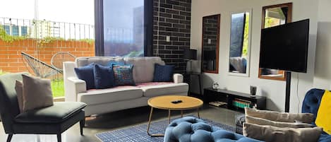 Un salon moderne avec un canapé, des fauteuils, une table basse et un téléviseur.