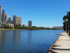A waterfront view with high-rise buildings, a clear sky, and a paved walkway along the water's edge. - [New] Ocean View 2 bedroom 2 bath in Waikiki (Honolulu)