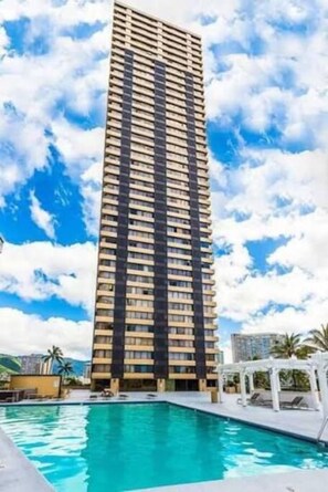 Un edificio alto con una piscina al frente.